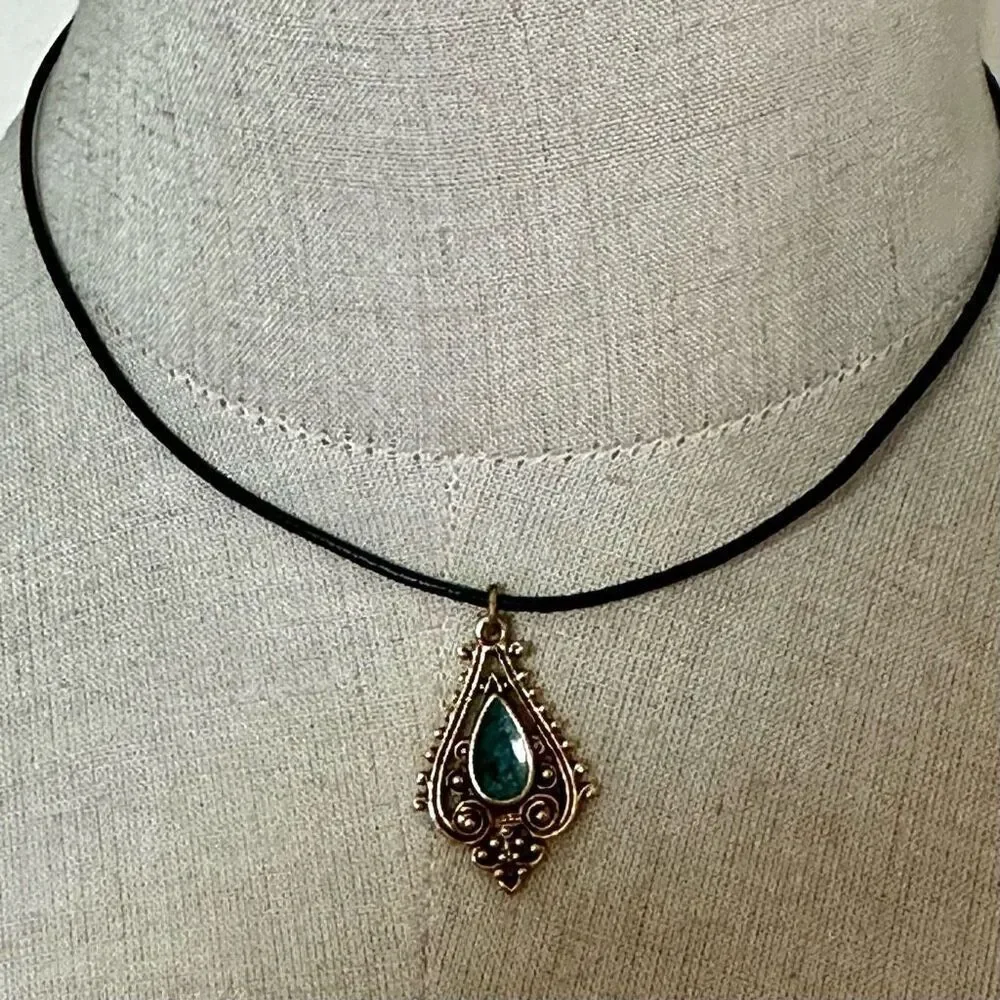 Green and gold tone pendant necklace on black cord